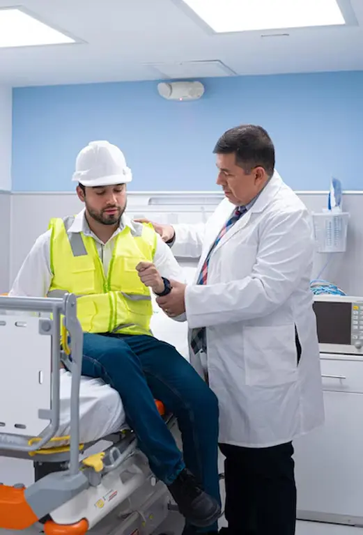Doctor revisando a un trabajador en una camilla sentado